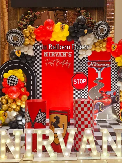 A detailed look at the Ferrari-themed birthday backdrop, complete with a road design, stop signs, and the baby's name in marquee lights.