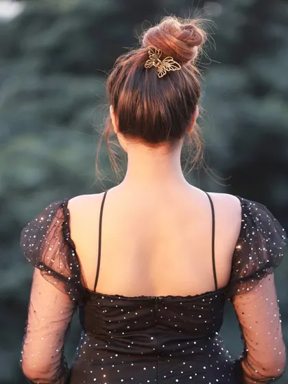 A detail shot from the same series, highlighting the butterfly hair clip and the back of the dress.
