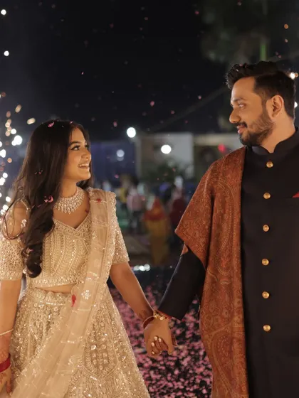 A romantic walk under the fireworks. The bride's makeup glows beautifully in the dramatic lighting.
