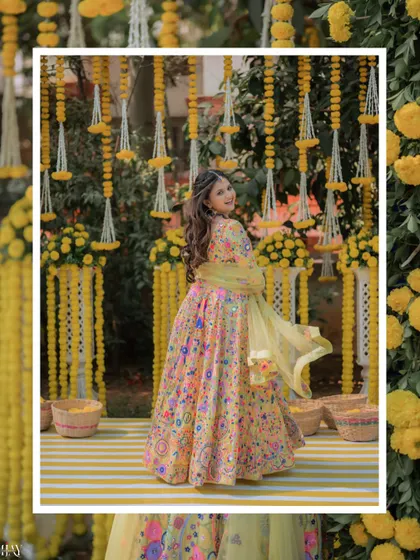 A beautiful shot of the bride twirling in her yellow lehenga, surrounded by marigold decorations.