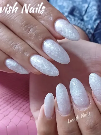 A full set of long, almond-shaped nails with a pearlescent white finish that has a subtle, textured effect, perfect for a sophisticated bride.