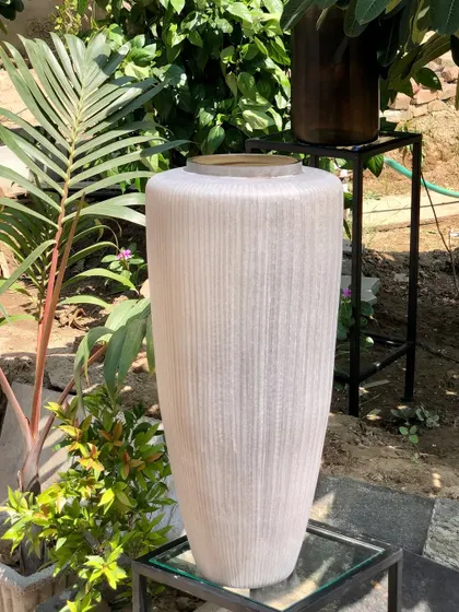 This tall, frosted glass vase, seen here in a garden setting, demonstrates how our pieces transition beautifully between indoor and outdoor spaces. Its simple, classic form is a canvas for nature itself.