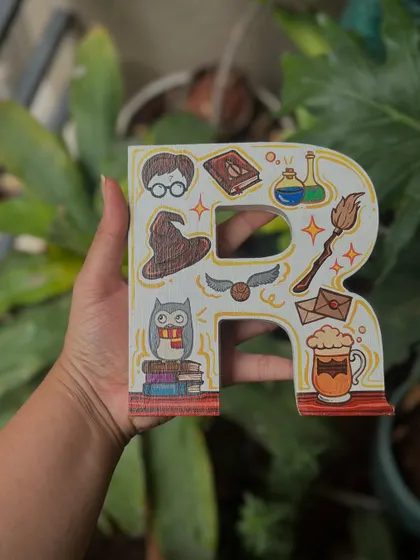 A Harry Potter-themed wooden letter 'R', decorated with iconic symbols from the series like the sorting hat, golden snitch, and a mug of butterbeer.