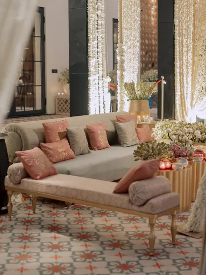 We create comfortable and stylish lounge areas for guests. This one features long sofas with a mix of pastel cushions, set against a backdrop of draped fabric and patterned flooring.