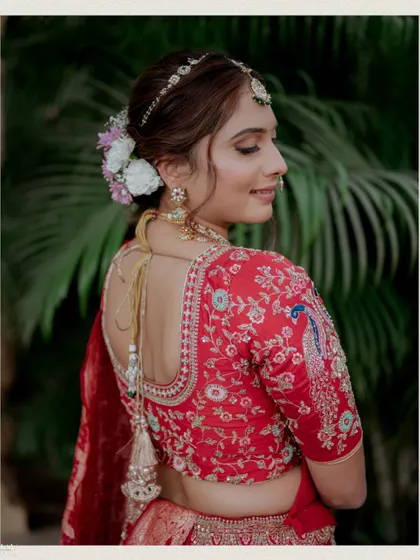 A close-up of the bride's blouse, showcasing the intricate embroidery and her beautiful floral hair accessory.