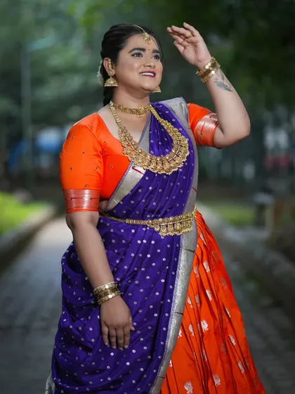 A close-up of the client's Navaratri look, showing the contrast between the bright orange blouse and the royal blue dupatta.