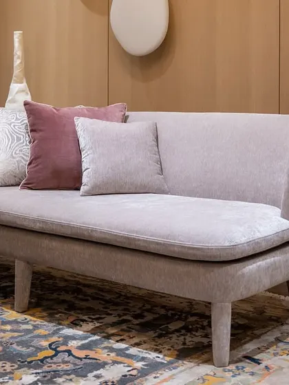 A custom-designed daybed in a soft, neutral fabric, perfect for lounging. The piece is part of a larger bedroom suite, offering a comfortable seating area within the personal space.