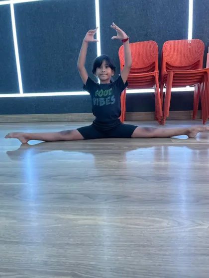 A young boy confidently holds a full middle split, showing that my classes are for everyone who wants to improve their physical abilities.