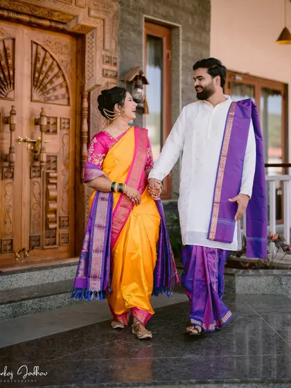 Ankita and Shantanu walking out of a traditional house, hand-in-hand, on their wedding day.