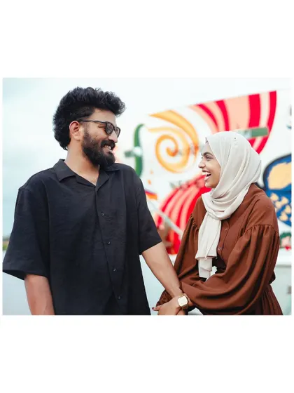 A beautiful, happy moment between the couple, their smiles lighting up the frame. The colorful background adds to the cheerful vibe.