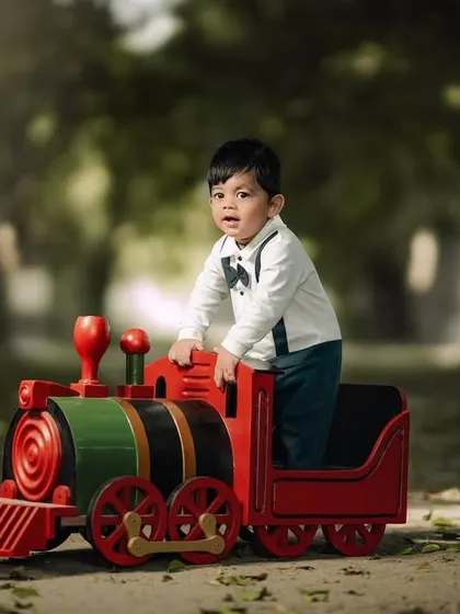 A handsome little conductor on his toy train. The path and trees create a beautiful, natural setting for this classic childhood portrait.