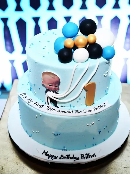 A detailed shot of a Boss Baby themed cake for a first birthday. The cake is decorated with the iconic character and a "First Trip Around The Sun" message, tying the theme together perfectly.