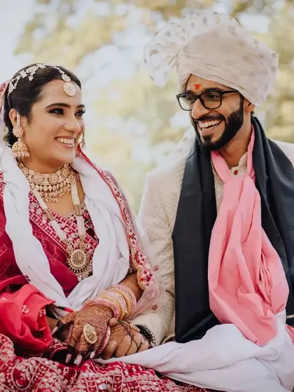 A happy, relaxed portrait of the couple seated together during their wedding, sharing a laugh.