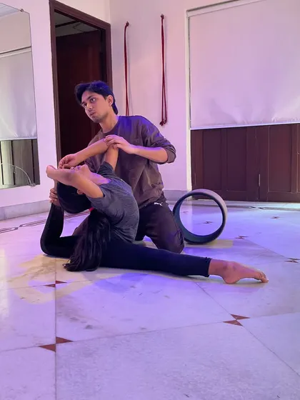 I provide hands-on assistance to ensure students practice safely and effectively. In this private session, I'm helping a young dancer deepen her flexibility for a King Pigeon Pose, using a yoga wheel for support.