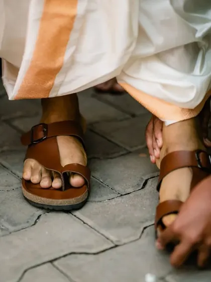 A detail shot of a wedding ritual involving the groom's feet, a significant part of some South Indian traditions.