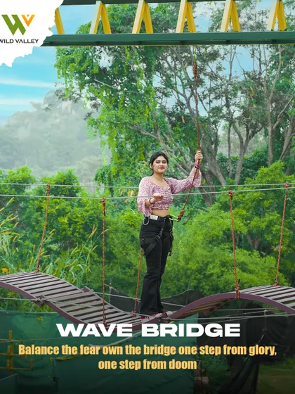A guest carefully balances on the Wave Bridge. This rope course element sways with every step, making it a fun and thrilling challenge for your coordination.