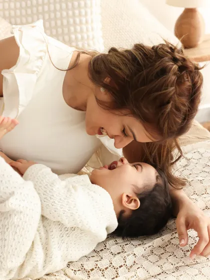A tender moment between mother and child. Lying on the bed and sharing a laugh, this image captures the simple, beautiful connection that is the heart of motherhood.
