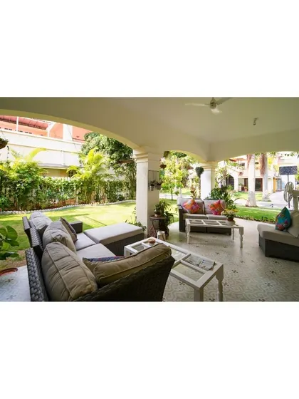 This expansive covered patio invites you to relax and unwind in nature's embrace, with comfortable outdoor sofas looking out onto a lush green lawn.