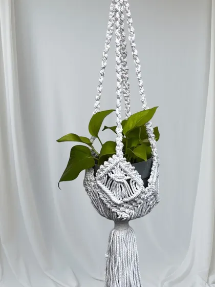 A classic white macrame plant hanger. The intricate design and long tassel make it a beautiful and elegant piece.