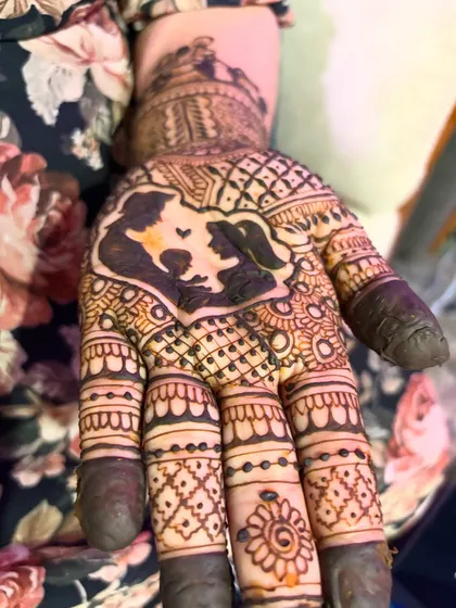 A close-up of a silhouette portrait for a baby shower mehendi. This design shows a couple with their baby, surrounded by delicate patterns, creating a beautiful and emotional centerpiece for the palm.