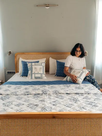 I love styling a bedroom to be a complete sanctuary. Here, I'm arranging cushions that coordinate with our quilted bedspread and curtains, all in a calming blue and white palette.