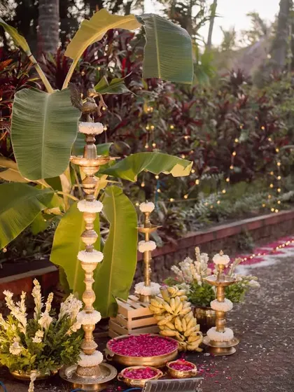 Traditional South Indian decor elements like banana plants and brass lamps marking the entrance to the wedding ceremony.