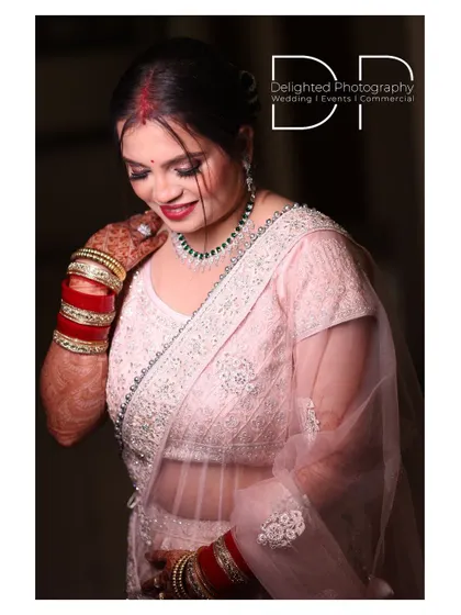 A beautiful portrait of a bride at her reception, showcasing her elegant light pink saree, traditional red and white bangles, and happy smile.