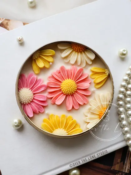 A close-up of a Daisy Urli featuring a warm, sunny color palette. The combination of pink, yellow, and ivory daisies makes this piece feel like a little burst of sunshine.