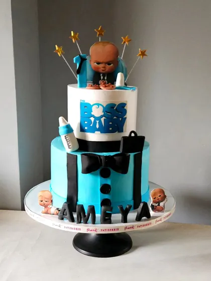 A stylish Boss Baby cake for a first birthday. This two-tiered design features a "suit and tie" bottom tier and a topper of the Boss Baby himself, complete with his briefcase and bottle.