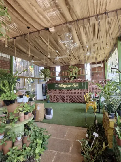 A wider shot of our cafe counter and entrance area. The combination of artificial grass, neon lights, and hanging plants creates a unique and welcoming first impression.