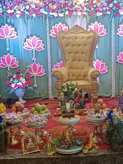 A lotus-themed stage decoration for a naming ceremony or baby shower. My gift platters, featuring peacock motifs and traditional dolls, are arranged to match the elegant and auspicious theme.