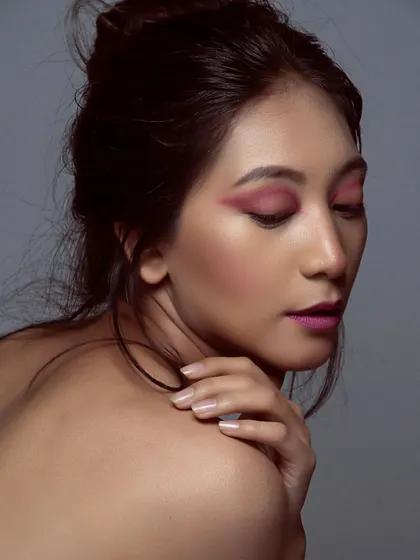 This profile shot highlights the vibrant pink eyeshadow and clean skin finish. The focus is entirely on the artistic makeup, showing how color can be used to create a powerful beauty statement.