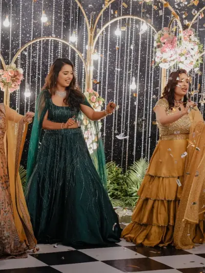 The bridesmaids light up the dance floor with their performance at a sangeet, set against a backdrop of sparkling light strings and floral arrangements.
