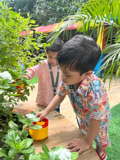 Children from our Red Butterfly class exploring the garden. The simple act of watering plants becomes a lesson in science, responsibility, and care.