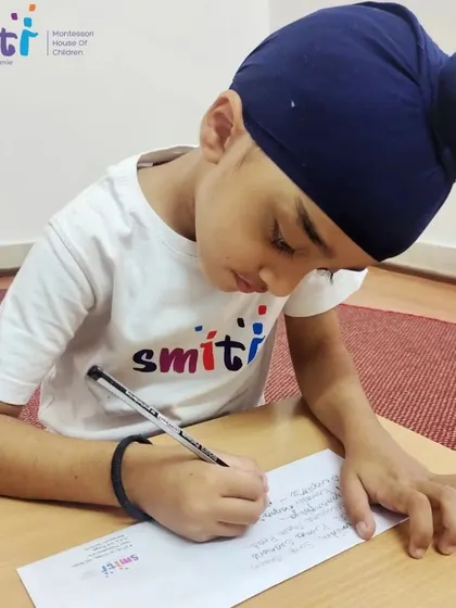 A student carefully writes a letter to his parents, inviting them to an upcoming school event. This was the first step in their hands-on lesson about the postal service.