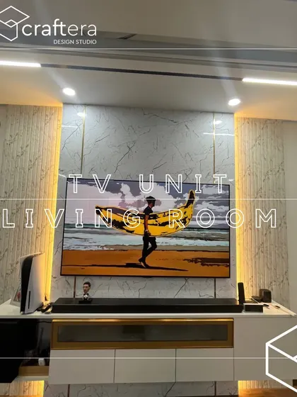 A close-up of a sleek TV unit design. The white marble-finish wall panel is accented with fluted sections and backlit for a soft glow, creating a sophisticated entertainment center.
