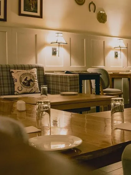 The Polo Lounge at the President Hotel features classic equestrian decor, including plaid upholstery and horse-themed artwork. The warm wood tables and soft lighting create a cozy, club-like atmosphere steeped in nostalgia.