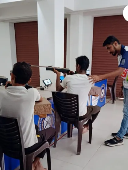 An instructor provides hands-on correction to a student's posture during a seated rifle shooting drill. This personalized coaching is key to building a strong technical foundation.