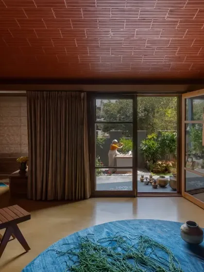 The living room in the Madhura house opens directly to the garden, centered around the Tulasi Brindavan. The combination of a yellow Jaisalmer stone floor and a terracotta vault roof fills the space with warmth.