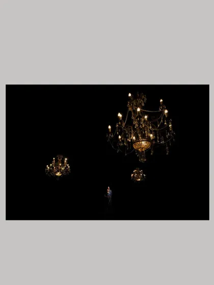 A minimalist and artistic shot, framing the couple amidst grand chandeliers against a black background for a dramatic effect.