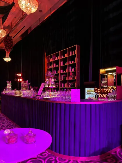 A stylish turquoise-themed bar counter with a modern, ribbed design, set under elegant chandeliers, perfect for a chic and musical evening.