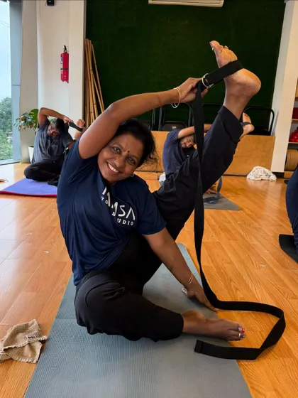 The joy of a deep stretch! A student uses a strap to work on her flexibility in a seated leg-raise pose.