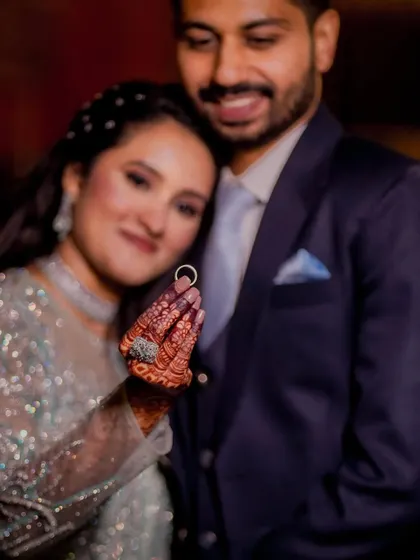 The promise of forever, perfectly framed. The bride proudly displays her engagement ring, with her and her partner sharing a happy, gentle moment in the background.