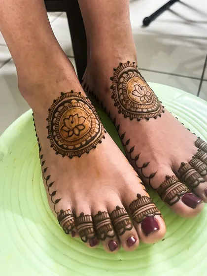 A minimalistic bridal leg mehendi with a central lotus mandala and simple, elegant patterns on the toes.