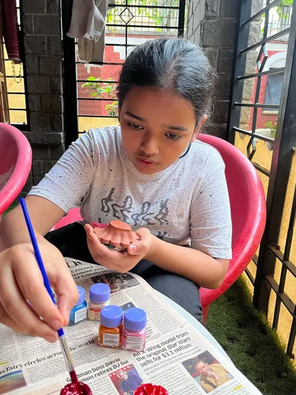 Getting into the festive spirit during our Diwali workshop. This young artist is carefully painting a traditional clay diya, adding her own creative touch to the celebration.