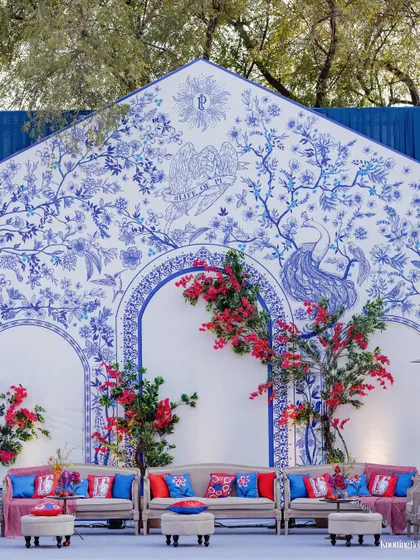A bold and artistic welcome lunch setup, featuring a backdrop of modern, abstract blue and white prints, accented with pops of red from bougainvillea.