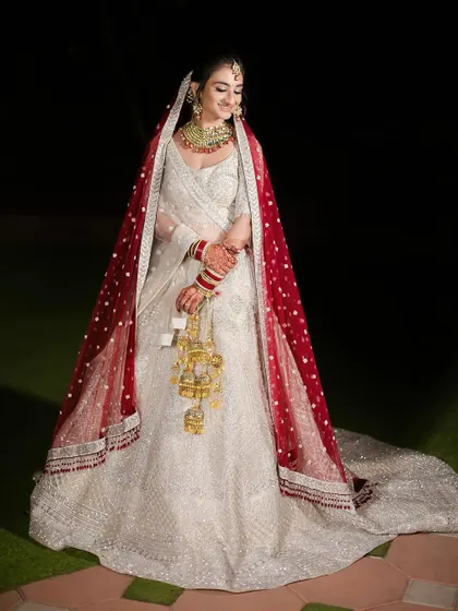 A vision in white. This bride chose a stunning white lehenga with a contrasting red dupatta, and she looks absolutely radiant and graceful as she smiles.