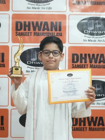 A young student proudly holds his certificate and trophy.