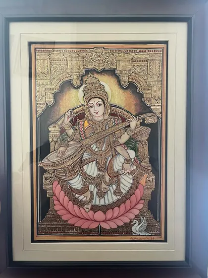 This captivating 10.5x15 inch depiction of Saraswathi Devi shows her elegantly seated, holding her Veena, with her swan by her side. It's a perfect piece to enhance any living space.
