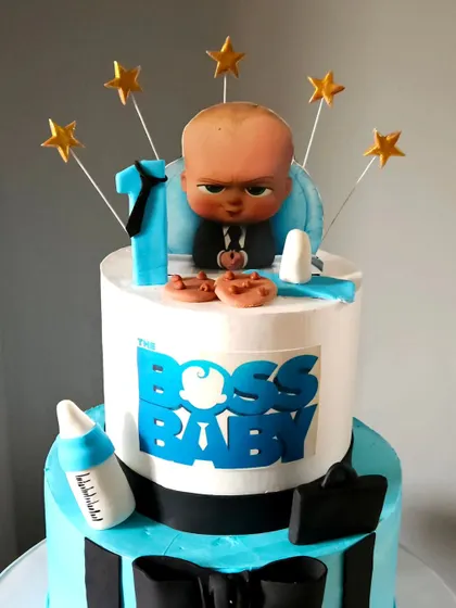 A close-up of the top tier of the Boss Baby cake, focusing on the detailed, edible printed topper of the Boss Baby himself.